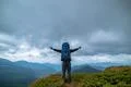 The happy man standing on the mountain on the rainy clouds background Photo