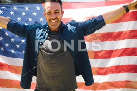 Happy man standing outdoors holding american flag Stock Photos