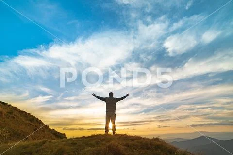 The happy man standing on the rock with a picturesque sunrise Stock Photos