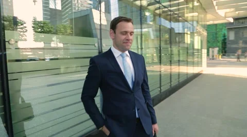 Happy man in a suit walking down the street, looking at the watch Stock Footage 68385067