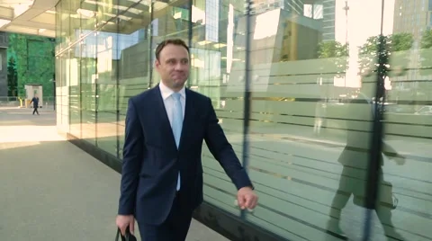 Happy man in a suit walking down the street, looking at the watch Stock Footage 68385097