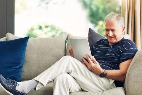 Happy man, tablet and scroll on couch with reading, story or editing digita.. Stock-Fotos