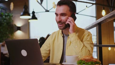 Happy man talking on the mobile or smart phone, while working with a laptop. Stock Footage 148873098