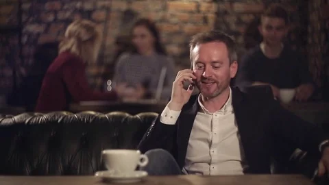 Happy man talking on smart phone on cafe and drinking coffee Video stock 69844765
