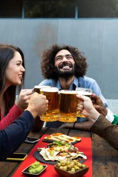 Happy man toasting with friends with beer outdoors. Celebratory toast. Vertical. Stock Photos