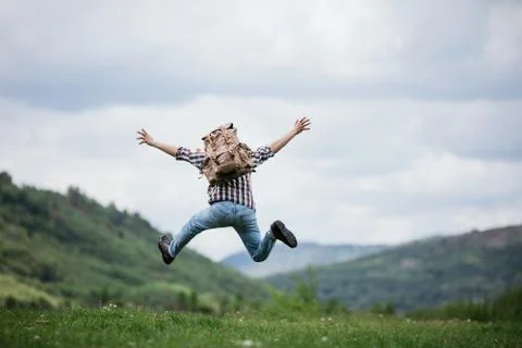 Happy Man traveler jumping with backpack in mountains active summer vacations Stock Photos