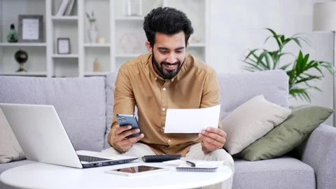Happy man uses mobile app for spending bills using smartphone on phone while sit Stock Footage 252214854