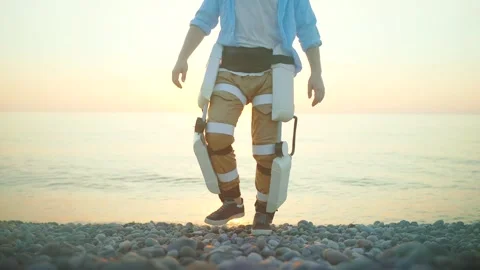 A happy man uses a mobile exoskeleton to move along the beach solving the Stock Footage 247996134