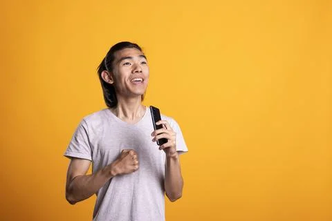 Happy man using cellphone as microphone during fun karaoke moment Stock Photos