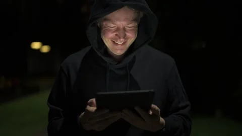 Happy man using digital tablet computer outdoors at night while smiling Stock Footage 317369066