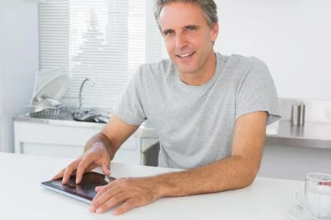 Happy man using digital tablet in kitchen Stock Photos