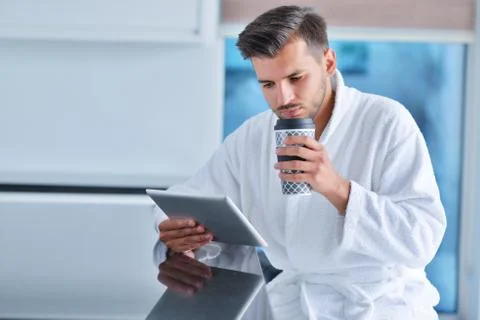 Happy man using digital tablet while having coffee in kitchen Stock Photos