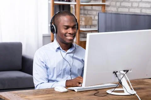 Happy Man Using Headphone While Working On Computer Foto stock