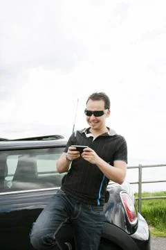 Happy man using his mobile outside his car Stock Photos