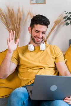 Happy man using laptop on sofa at home in a video call Stock Photos