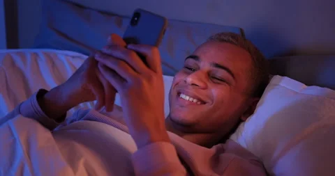 Happy man using mobile phone in bed at night Stock Footage 145289665