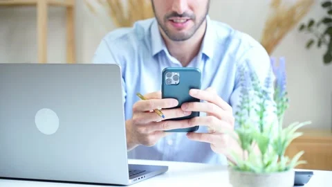 Happy man using smartphone and laptop at home Stock Footage 228946929