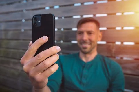 Happy man using smartphone. Facetime video call. Looking at smartphone Stock Photos