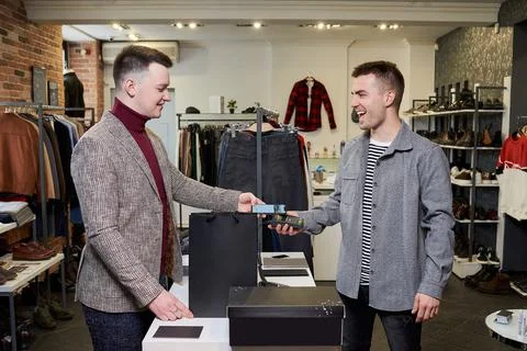 A happy man is using a smartphone to pay by wireless NFC technology for purch Stock Photos