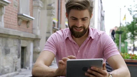 Happy man using tablet drinking coffee at outdoors cafe Stock Footage 102384930