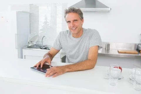 Happy man using tablet pc in kitchen Stock Photos