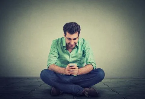 Happy man using texting on smartphone sitting on floor of his apartment 스톡 사진