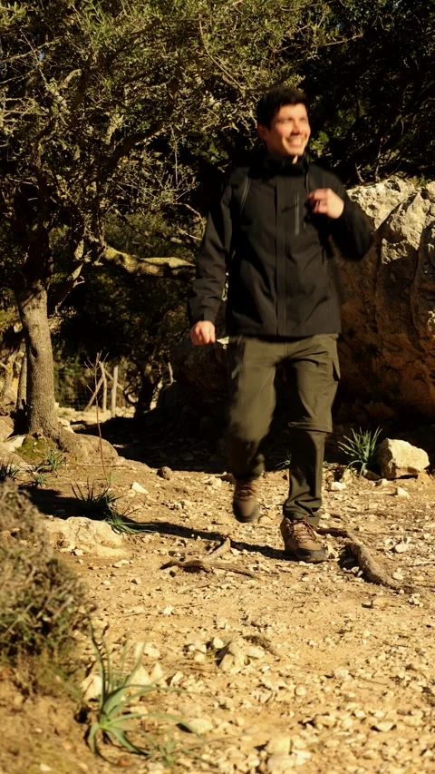 Happy man walking on a rocky path in the mountains Stock Footage 296273475