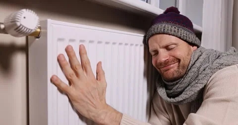Happy man warming in front of radiator in cold room at home when heating se.. Stock Footage 322172511