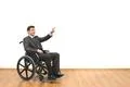 The happy man in a wheelchair gesturing on the white wall background Photo