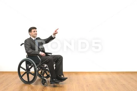 The happy man in a wheelchair gesturing on the white wall background Stock Photos