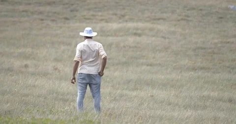 Happy man in white hat standing at the middle of the field raising hands up Way Stock Footage 94416113