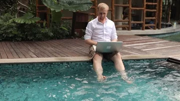 Happy man working behind laptop sitting by the pool 스톡 동영상 85934091