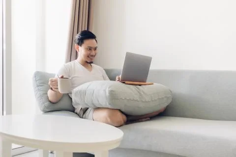 Happy man is working on the sofa in concept of work at home. Фото