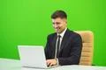 The happy man works with the laptop on the green background Photo