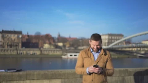 Happy man writing message on smartphone app, walks up and goes away, river Vídeos de archivo 72710353
