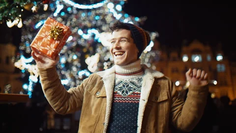 Happy man with a xmas gift dancing at old town square on Christmas. new year Stock Footage 166095437