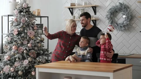 Happy married couple with children using smart phone talking Merry Christmas. Stock Footage 142662302
