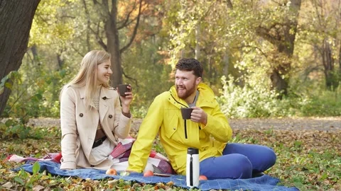 A happy married couple drinks tea, coffee, during a romantic picnic in the Stock Footage 237913200