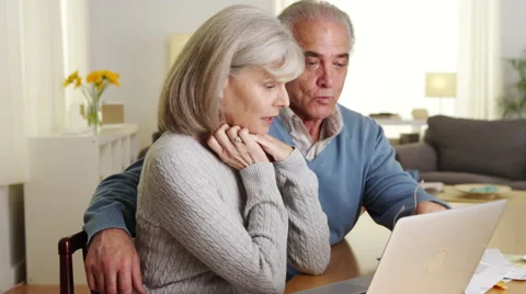 Happy mature couple using laptop computer to pay bills Stockbeeldmateriaal 47383572