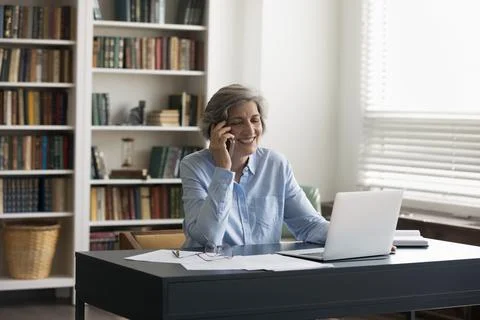 Happy mature elderly 50s business professional lady answering cellphone call Stock Photos