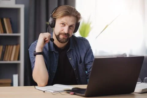 Happy mature man in headset sitting at table with laptop Stock Photos