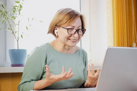 Happy mature woman in eyeglasses talking using video conference call application Stock Photos