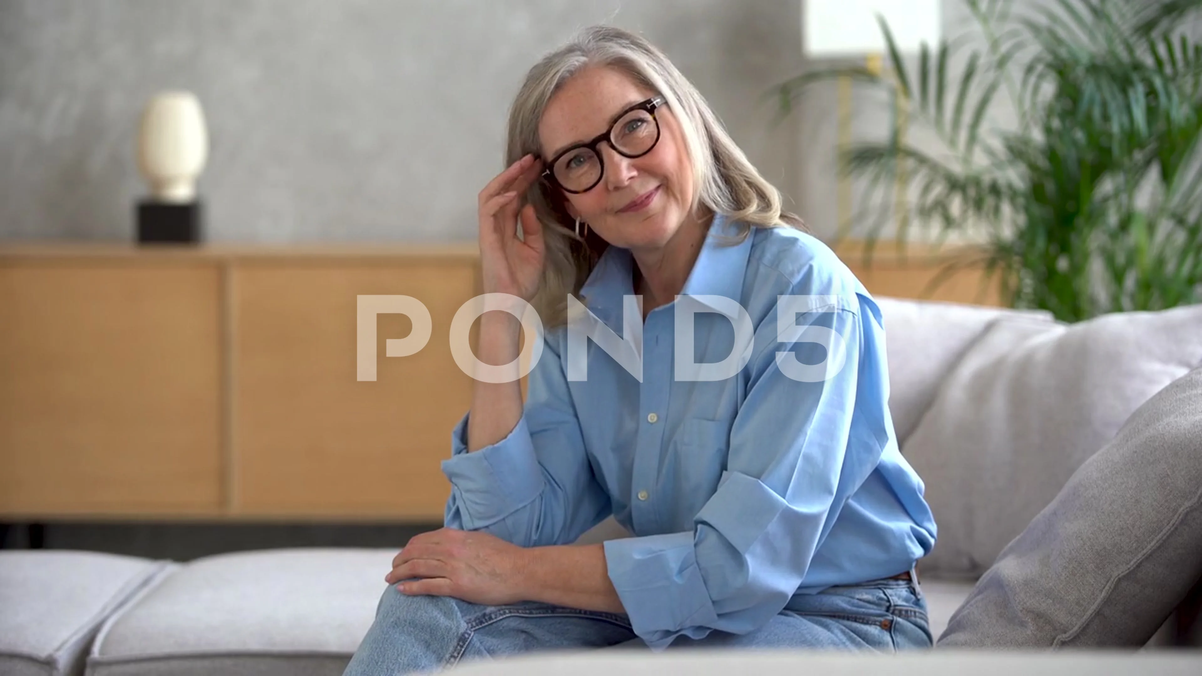 Happy mature woman looking at camera posing at home for video portrait