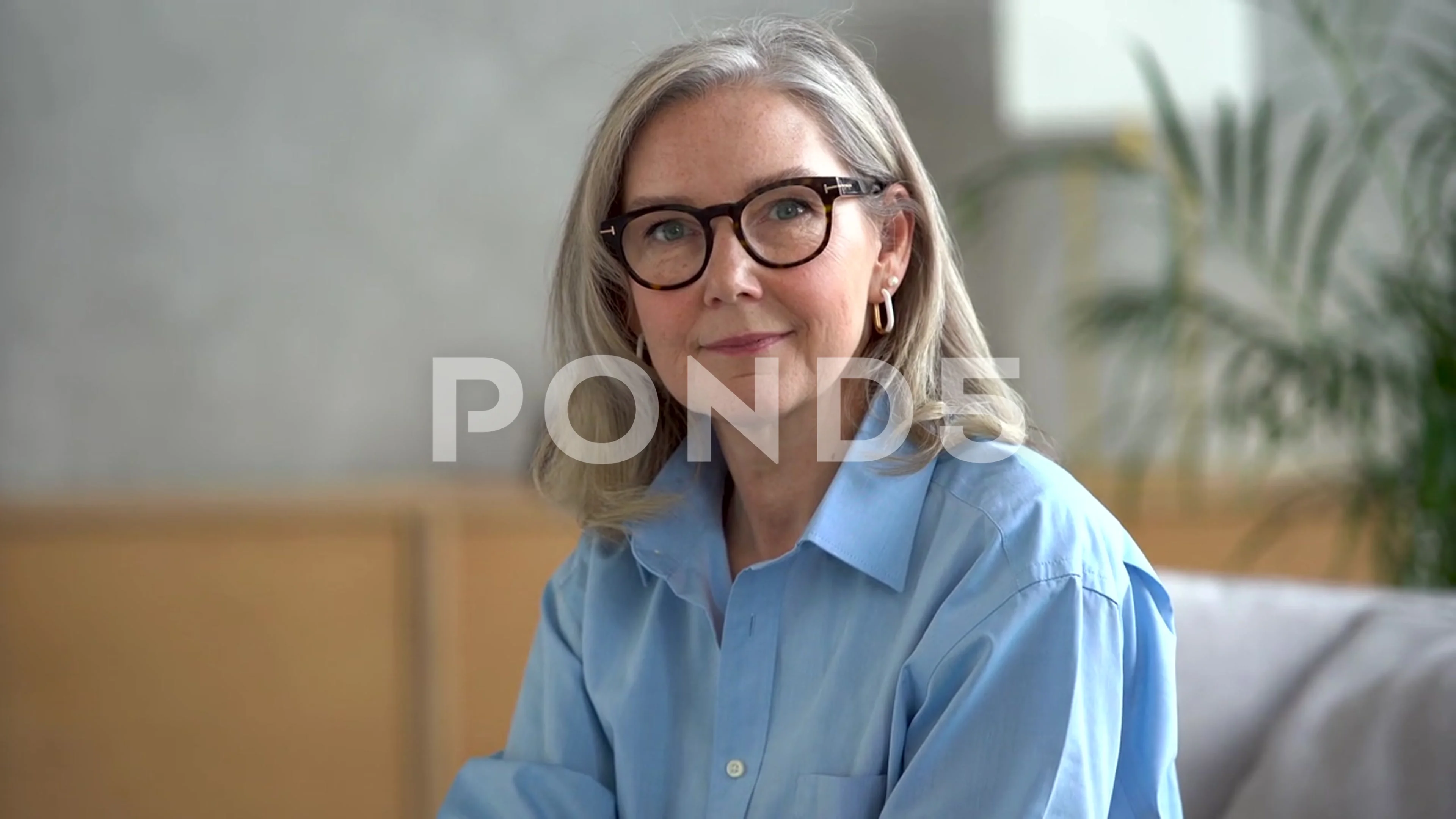 Happy mature woman looking at camera posing at home for video portrait