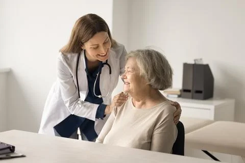 Happy medical worker touch older lady shoulder express support Stock Photos