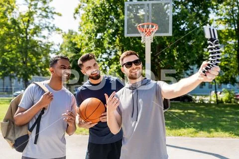 Happy men taking selfie at basketball playground Stock Photos