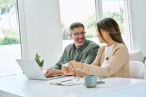 Happy mid aged couple using laptop computer holding credit card buying online. Stock-Fotos