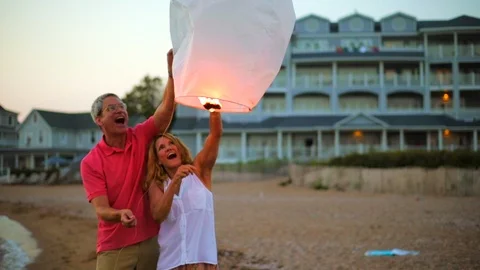 Happy middle aged couple playing with a glowing lantern on a beach. Vidéo 88404765