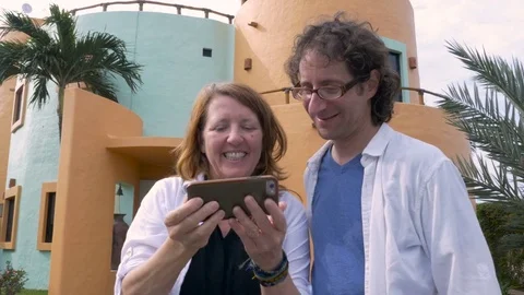 A happy middle aged couple take selfies in front of their new house Stock Footage 73127218
