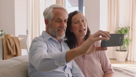 Happy middle aged couple using smartphone having video chat blowing kiss at Stock Footage 103487656